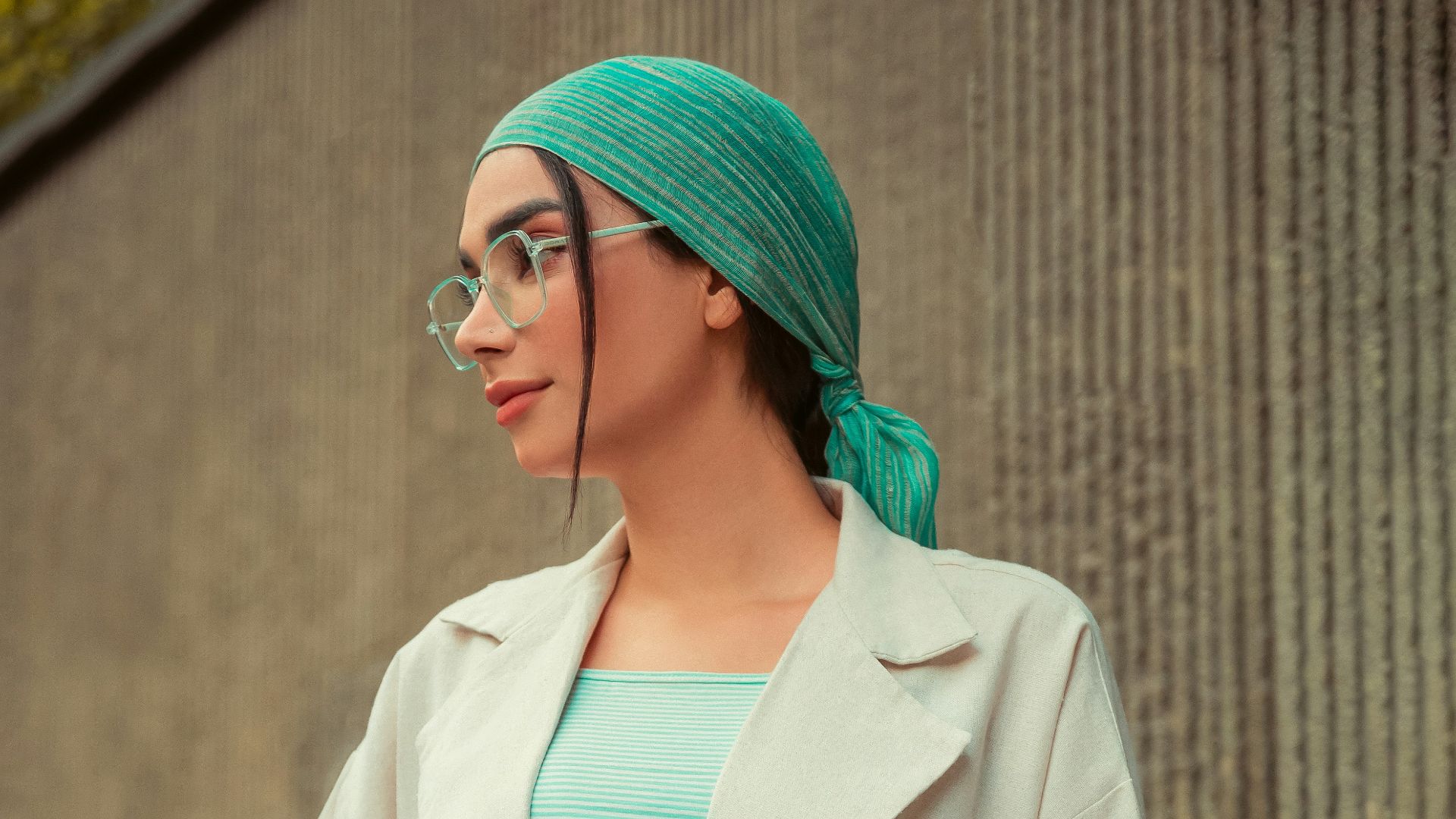 Woman poses stylishly in a light-colored outfit.